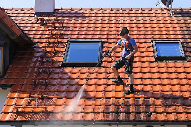 worker is cleaning the roof and rainwater gutter with high pressure.